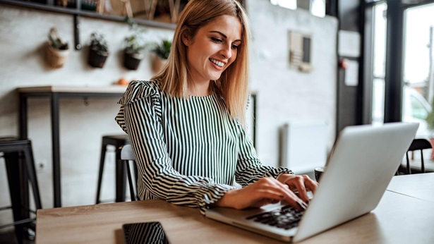 Smiling woman typing on laptop indoors.